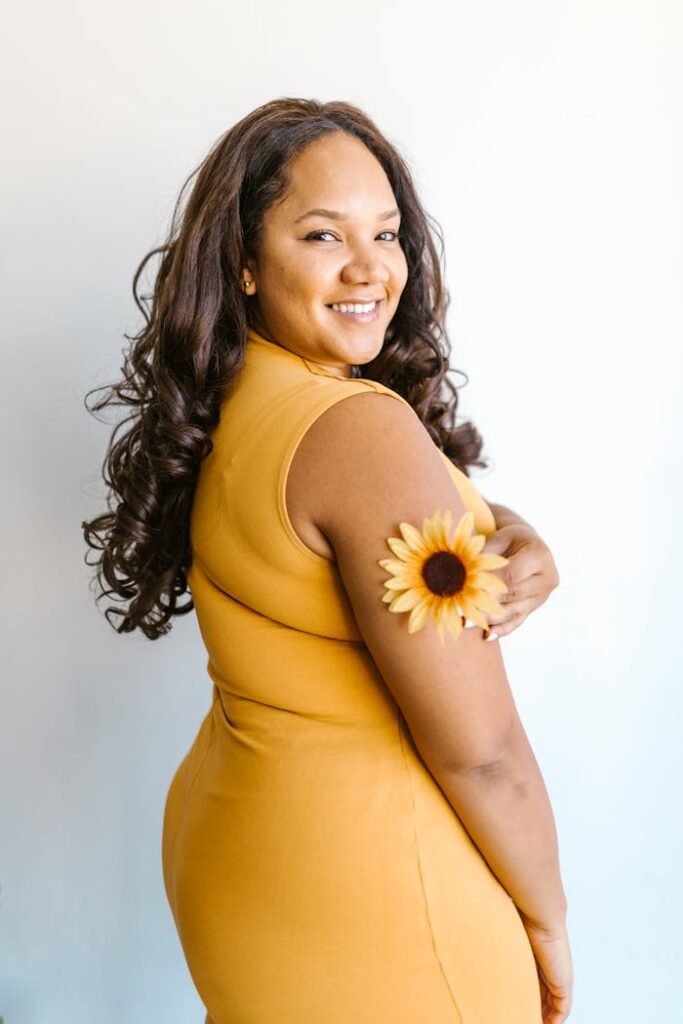 Confident woman in orange dress with sunflower, showcasing positivity and fashion.